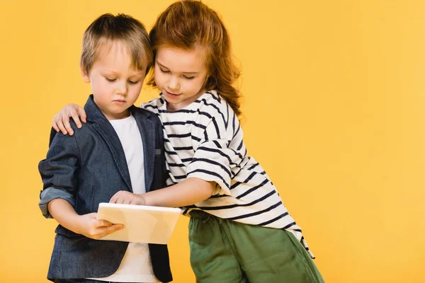 Ritratto di bambini che usano la compressa insieme isolati sul giallo — Foto stock