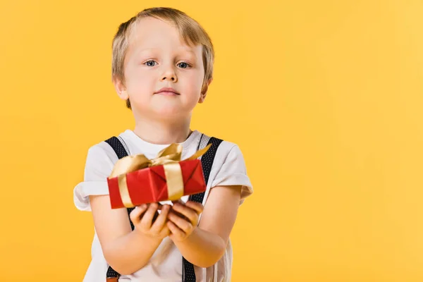 Selective focus of little boy with wrapped present isolated on yellow — Stock Photo