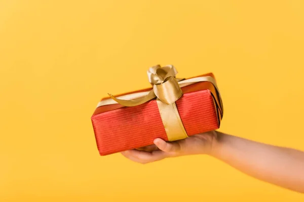 Tiro recortado de niño sosteniendo regalo envuelto aislado en amarillo - foto de stock