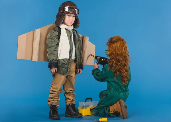 Kids in pilot costumes with toy screwdriver playing together isolated on blue — Stock Photo