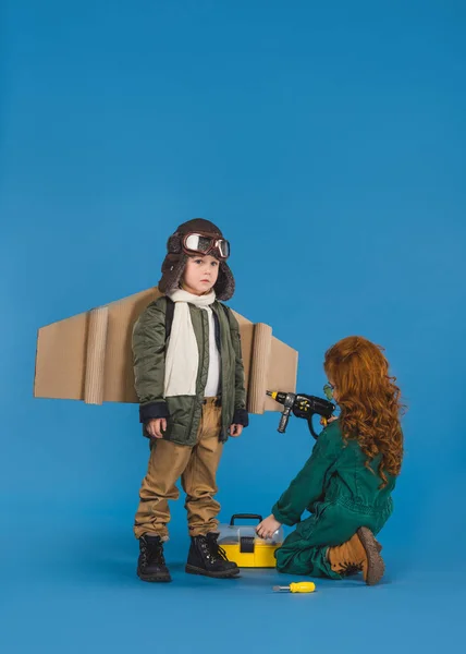Діти в пілотних костюмах з іграшковою викруткою грають разом ізольовано на синьому — стокове фото