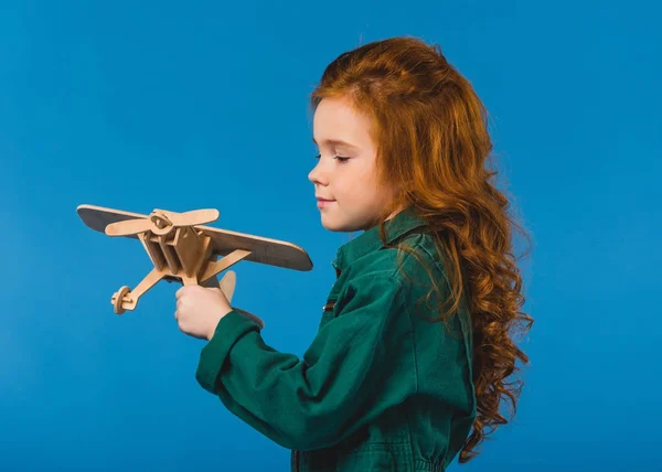 Portrait d'adorable enfant en costume de pilote avec jouet en bois isolé sur bleu — Photo de stock