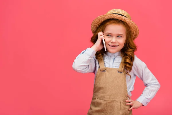 Портрет маленького улыбающегося ребенка, говорящего на смартфоне, изолированного на розовом — стоковое фото