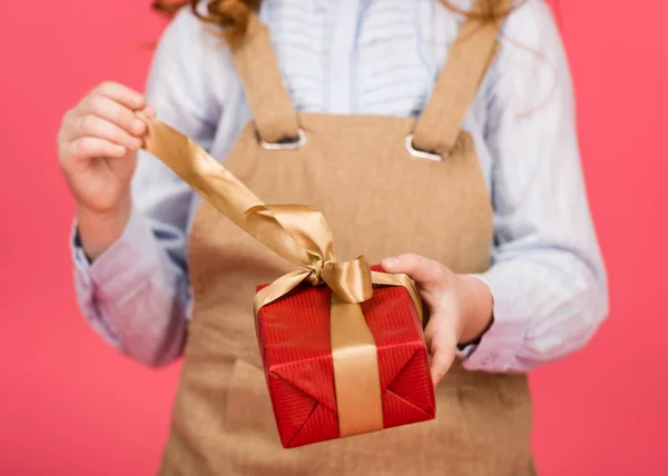 Tiro recortado de niño con regalo envuelto en manos aisladas en rosa - foto de stock