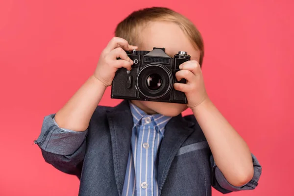 Vista oscurecida del niño sosteniendo la cámara fotográfica aislada en rosa - foto de stock