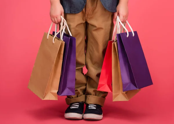Vista parcial de los niños y bolsas de compras aisladas en rosa - foto de stock