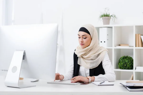 Retrato de una mujer de negocios musulmana enfocada que trabaja en la computadora en la oficina - foto de stock