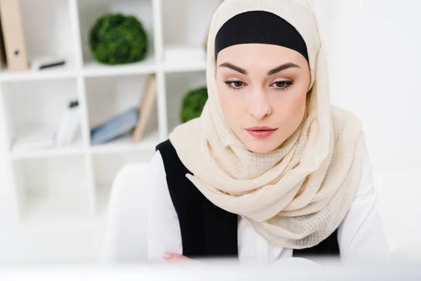 Portrait of beautiful pensive businesswoman in hijab in office — Stock Photo