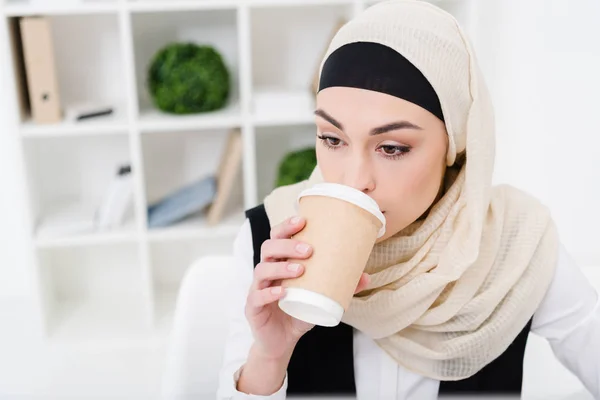Retrato de una mujer de negocios musulmana en hiyab bebiendo café en la oficina - foto de stock