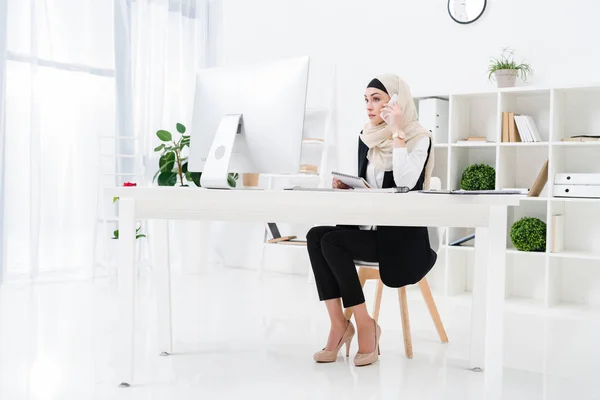 Geschäftsfrau im Hidschab telefoniert am Arbeitsplatz im Büro mit dem Smartphone — Stockfoto