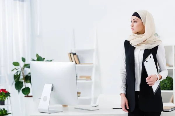 Donna d'affari araba pensosa con cartella in mano in ufficio — Foto stock