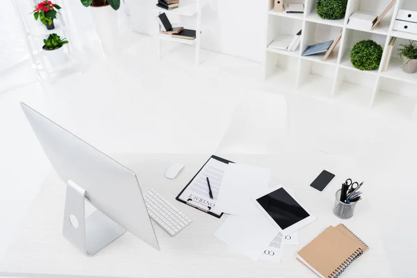 High angle view of computer screen, digital devices, contract and notebooks on table in office — Stock Photo