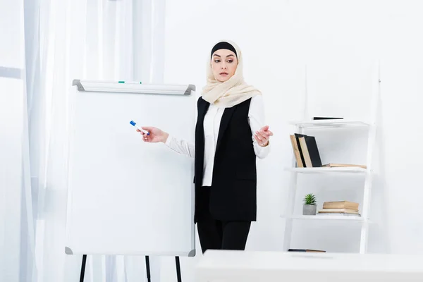 Focada mulher de negócios muçulmana no hijab apontando ay white board no escritório — Fotografia de Stock