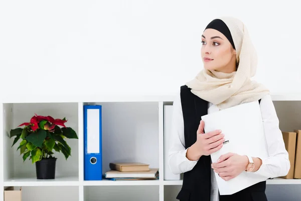 Портрет задумчивой бизнесвумен в хиджабе с папкой в офисе — стоковое фото