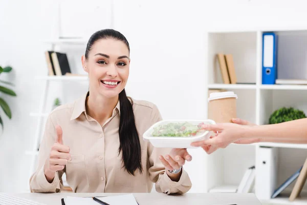 Ritratto di donna d'affari sorridente che mostra il pollice in su mentre porta via il cibo dal corriere in ufficio — Foto stock