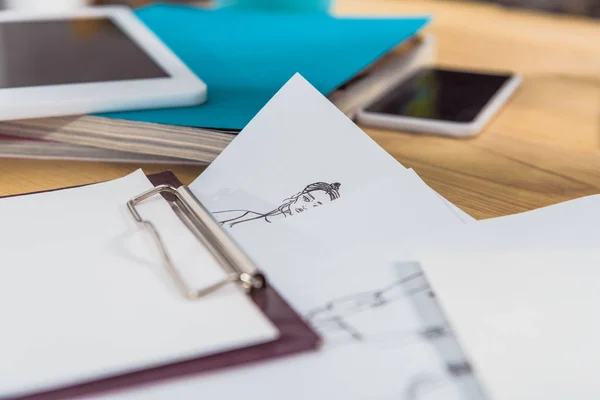 Fashion sketches and clipboard on working table — Stock Photo