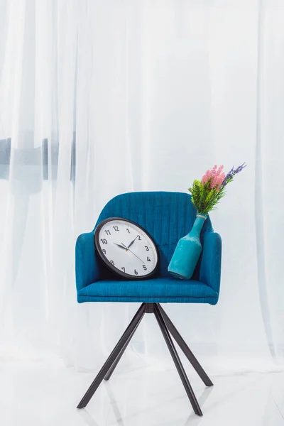 Vase et horloge en chaise moderne bleue dans la chambre devant la fenêtre — Photo de stock