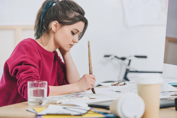 Attractive young girl drawing sketches by working table — Stock Photo