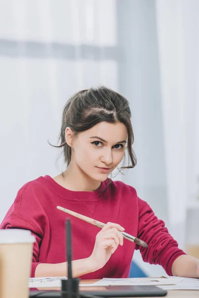 Smiling artist holding brush and looking at camera — Stock Photo