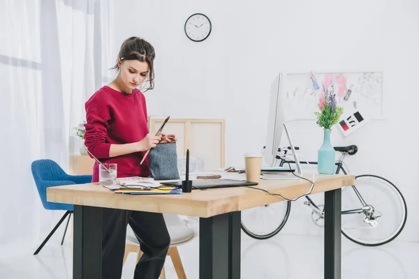 Young woman with illustrations by working table with computer — Stock Photo