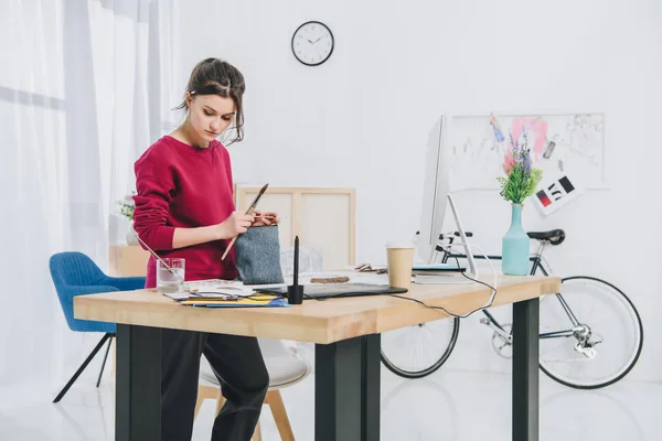 Mujer joven con ilustraciones por mesa de trabajo con ordenador — Stock Photo