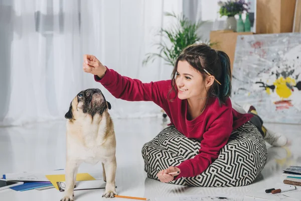 Young girl playing with pug on floor of modern home office — Stock Photo