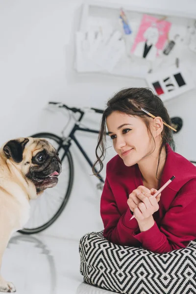 Young woman artist looking at pug dog — Stock Photo