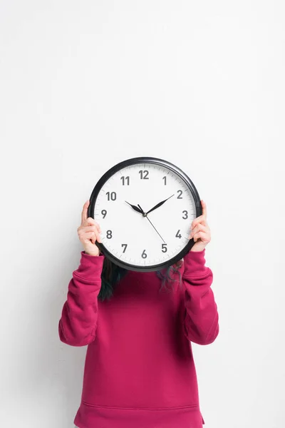 Chica sosteniendo reloj sobre su cara aislado en blanco - foto de stock