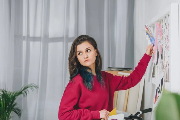 Muchacha joven atractiva fijando bocetos en el tablero del humor - foto de stock