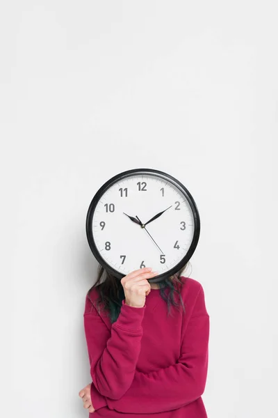 Жінка тримає годинник над її обличчям ізольовано на білому — стокове фото