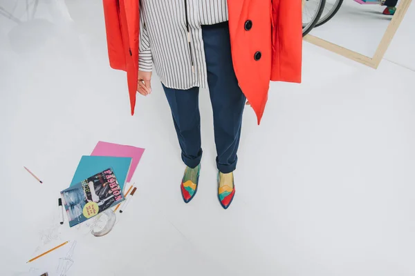Обрезанный вид женских ног в яркой обуви журналами на полу — стоковое фото