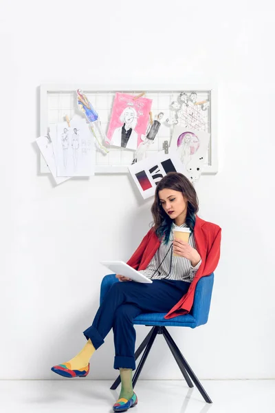 Linda dama trabajando en la tableta y sosteniendo la taza de café en el estudio de luz - foto de stock