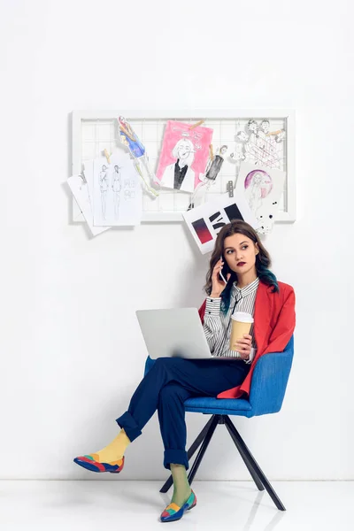 Attractive young girl talking on the phone while working on laptop — Stock Photo