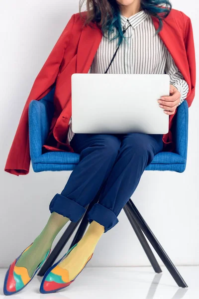 Vue rapprochée de la jeune fille travaillant sur un ordinateur portable alors qu'elle était assise sur une chaise — Photo de stock