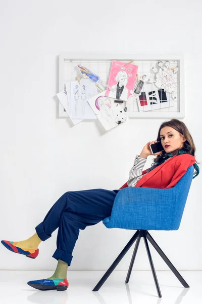 Mujer joven hablando por teléfono mientras está sentada en la silla - foto de stock