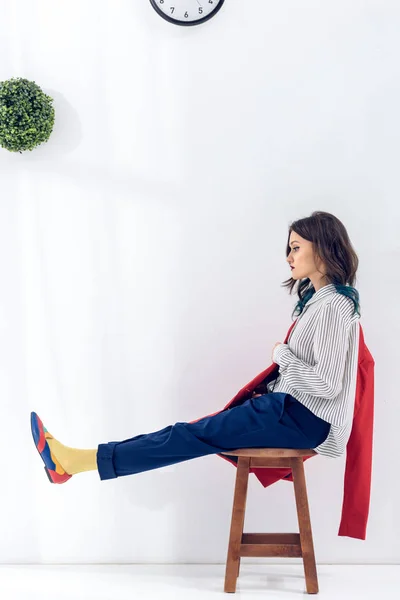 Attraktives junges Mädchen sitzt auf Stuhl unter Uhr — Stockfoto