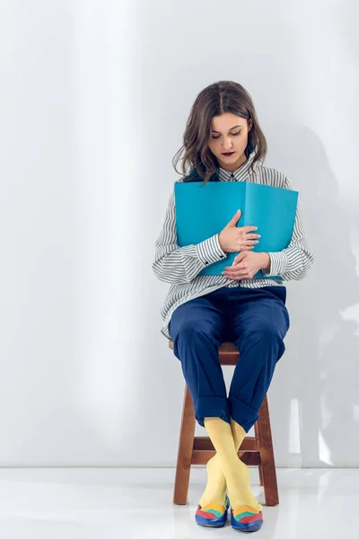 Mujer joven sentada en silla y leyendo libro - foto de stock