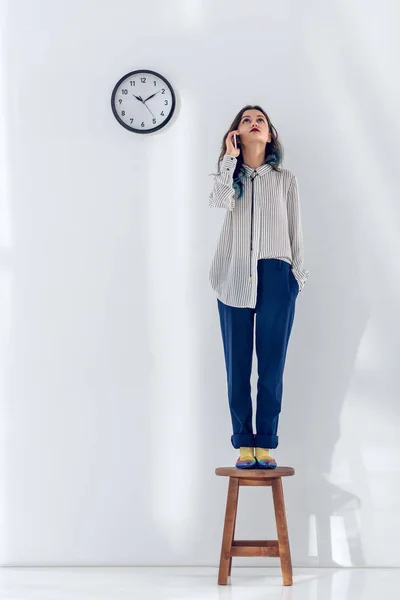 Linda senhora falando ao telefone enquanto está de pé na cadeira — Fotografia de Stock