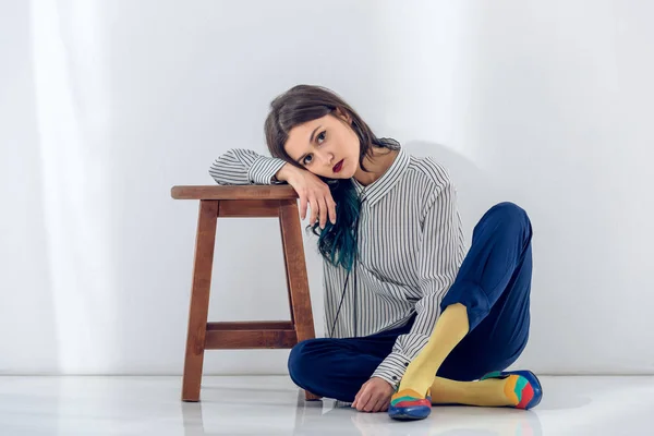 Молодая женщина, сидящая на полу возле деревянного стула — стоковое фото