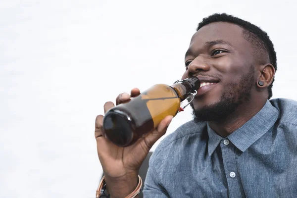 Hombre afroamericano guapo bebiendo cerveza de botella - foto de stock