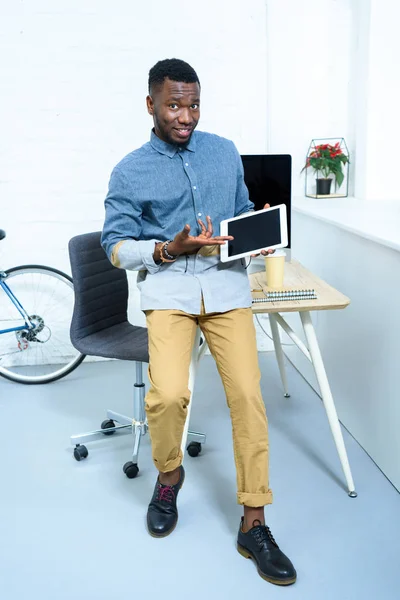 Молодой человек показывает на цифровом экране планшета стоя в домашнем офисе — стоковое фото