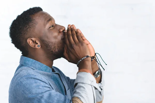 Hombre afroamericano guapo con las manos dobladas por la cara - foto de stock