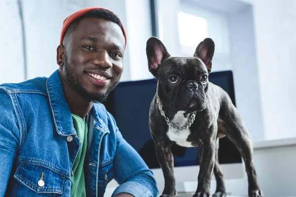 Young man with French bulldog by computer screen — Stock Photo