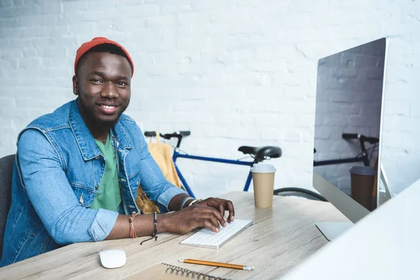 Bonito homem afro-americano digitando no teclado por mesa de trabalho — Fotografia de Stock