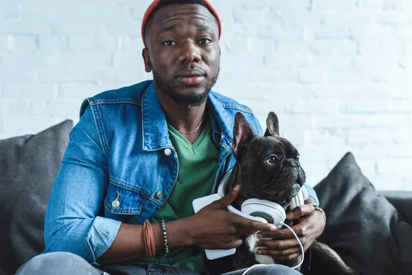 Young man wearing headphones on Frenchie dog — Stock Photo