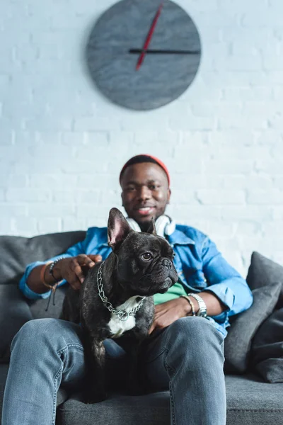 Schöner afrikanisch-amerikanischer Mann mit Kopfhörern kuschelt französische Bulldogge — Stockfoto