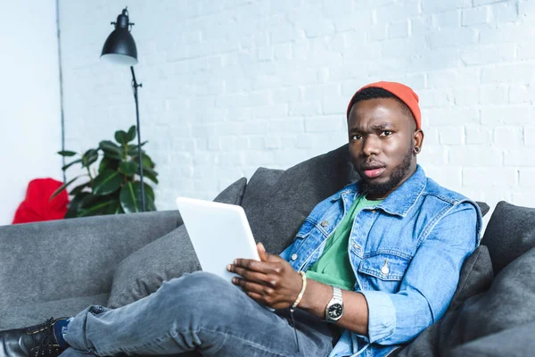 Junger Mann hält digitales Tablet in der Hand und blickt in Kamera — Stockfoto