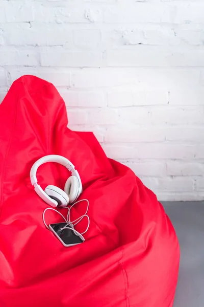 Smartphone avec casque sur sac haricot rouge — Photo de stock