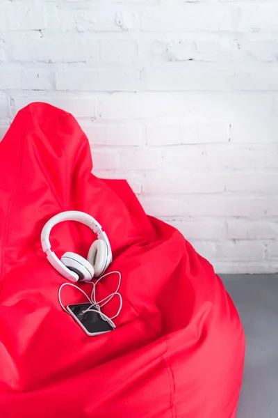 Smartphone con auriculares en bolsa de frijol rojo - foto de stock