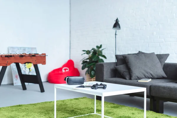 Digital gadgets on table in modern room with sofa — Stock Photo